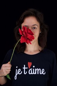 Close-up of woman holding rose against black background