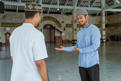 Smiling man welcoming friend at mosque