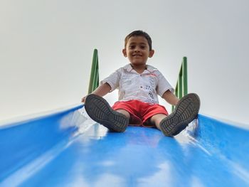 Young boy sitting on top of a baby slide. cute smiling 5 years teen boy portrait