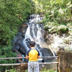 Rear view of man standing against waterfall