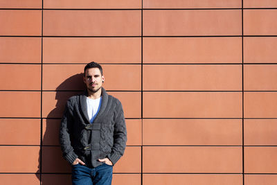 Front view of a fashionable young man standing against orange wall