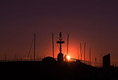Silhouette cranes against sky during sunset