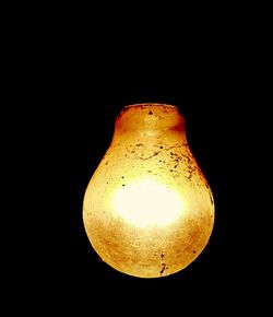 Close-up of illuminated light bulb against black background