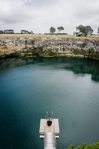 High angle view of woman sitting at lake against sky