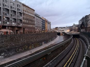 Railroad tracks amidst buildings in city against sky