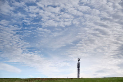 Low angle view of communications tower on field against sky