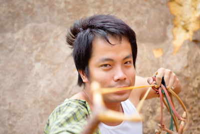 Portrait of young man holding camera outdoors