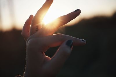 Close-up of hand holding sun during sunset