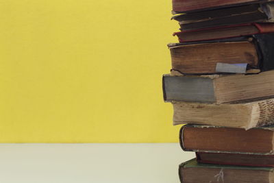 Close-up of stack of books on table against wall