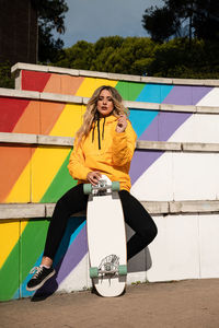 Portrait of a cheerful woman with a skateboard on colorful stairs