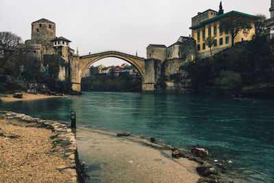 Arch bridge over river against buildings