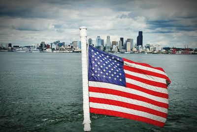 Flag against buildings and sea against sky