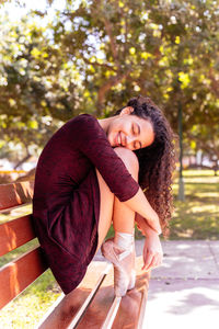 Portrait of smiling young woman against trees