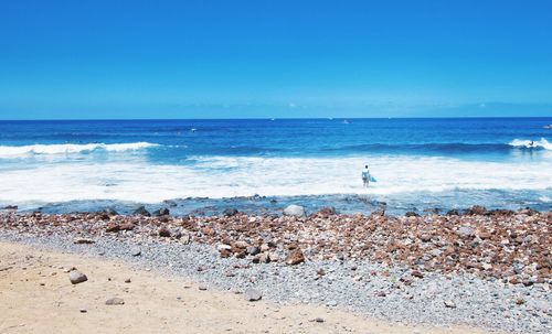 Scenic view of beach against clear blue sky