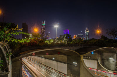 Illuminated bridge over city against sky at night