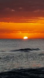 Scenic view of sea against dramatic sky during sunset