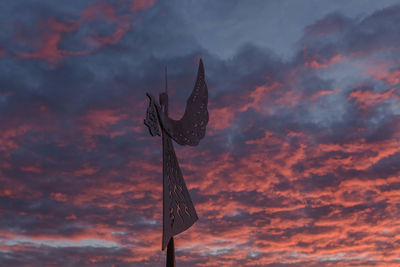 Low angle view of silhouette communications tower against dramatic sky