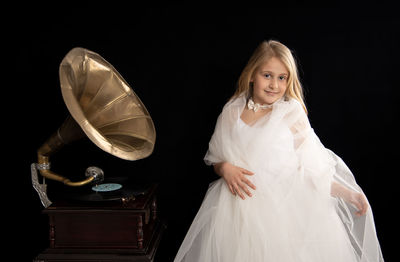 Portrait of girl standing against black background