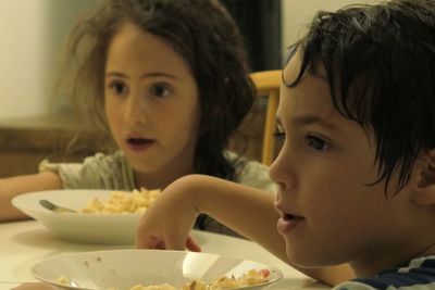 Cute siblings eating food at home