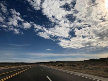Road passing through landscape against cloudy sky