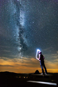 Man standing by light painting against sky at night