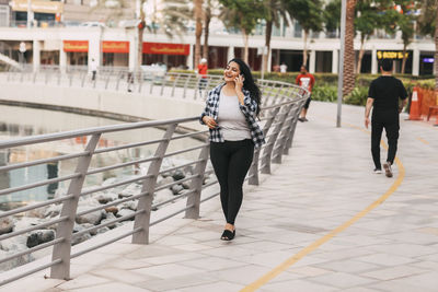 An indian girl walks along the embankment and talks on the phone.