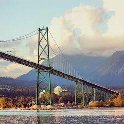 Bridge over river against cloudy sky