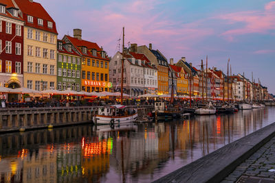 Sailboats in river by buildings in city against sky