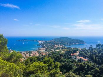 Scenic view of sea and trees against blue sky