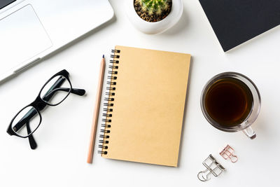 High angle view of laptop with office supplies and coffee on white background