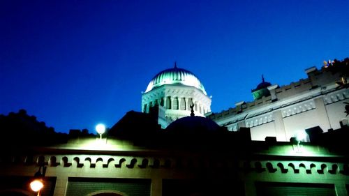 Low angle view of illuminated building against clear blue sky