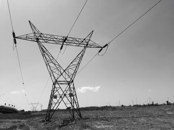 Low angle view of electricity pylon on field against sky