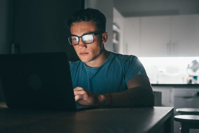 Portrait of young man using laptop at desk in office