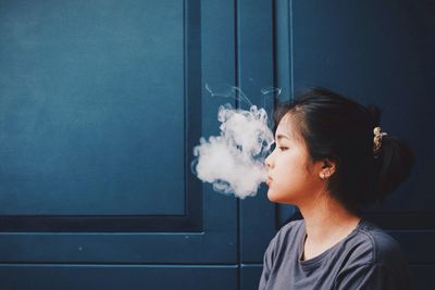 Woman smoking against door