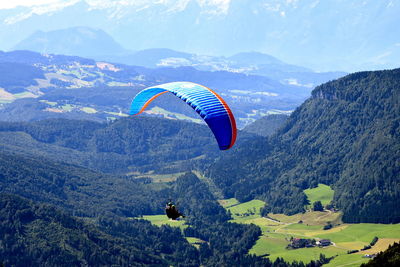 Aerial view of people paragliding against mountain range