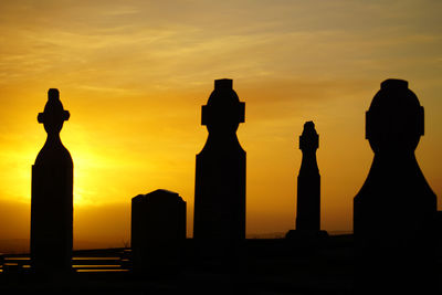Silhouette graveyard cemetery  against sky during sunset
