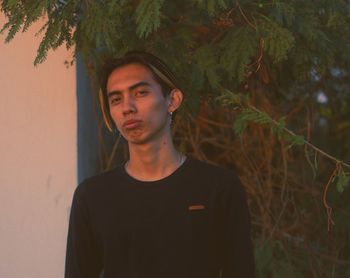 Portrait of young man standing against plants