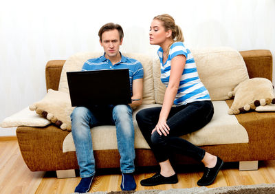Friends sitting on sofa at home
