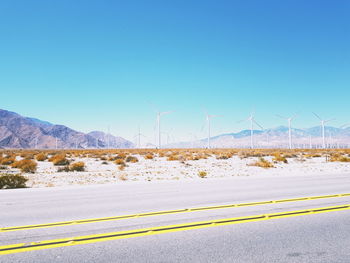 Wind turbines on landscape against clear blue sky
