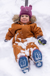 Portrait of cute girl sitting on snow covered field