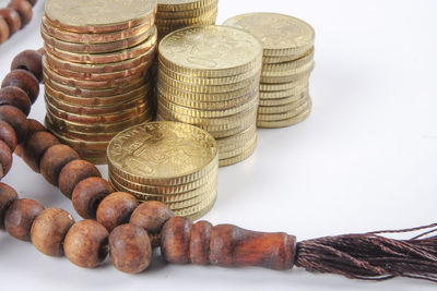 High angle view of rosary beads with stacked coins on gray background