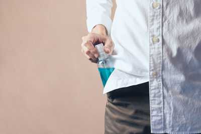 Midsection of man standing against white wall