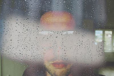 Close-up of waterdrops on glass a man
