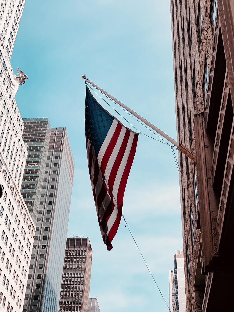 LOW ANGLE VIEW OF FLAGS AND BUILDINGS AGAINST SKY