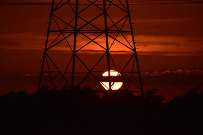 Low angle view of silhouette electricity pylon against sky at sunset