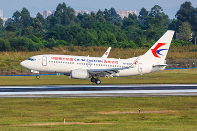 Side view of airplane on airport runway against sky