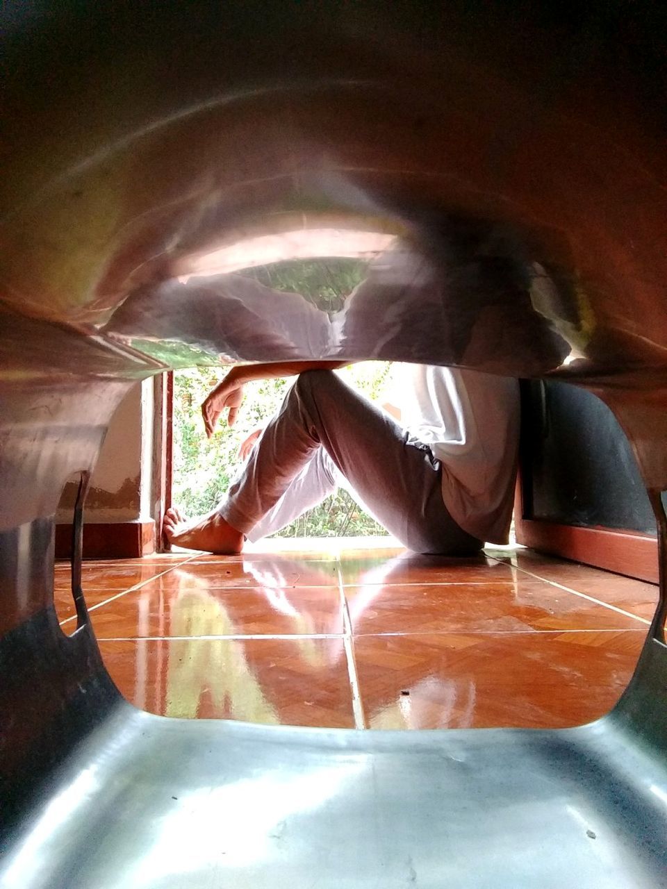 REFLECTION OF WOMAN SITTING ON FLOOR IN GLASS