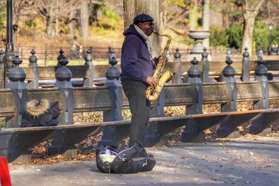 Side view of man playing trumpet while standing on road