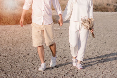 Low section of couple walking on footpath