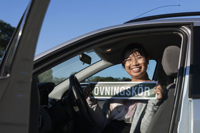 Female student driver holding sign